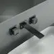 Wandarmatur in mattem Schwarz für Waschbecken, montiert an der Wand mit eckigen Rosetten. Ideal Standard Produkt mit zwei Drehgriffen zur Wasserregelung.